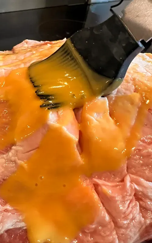 Brushing a golden glaze over the scored pork