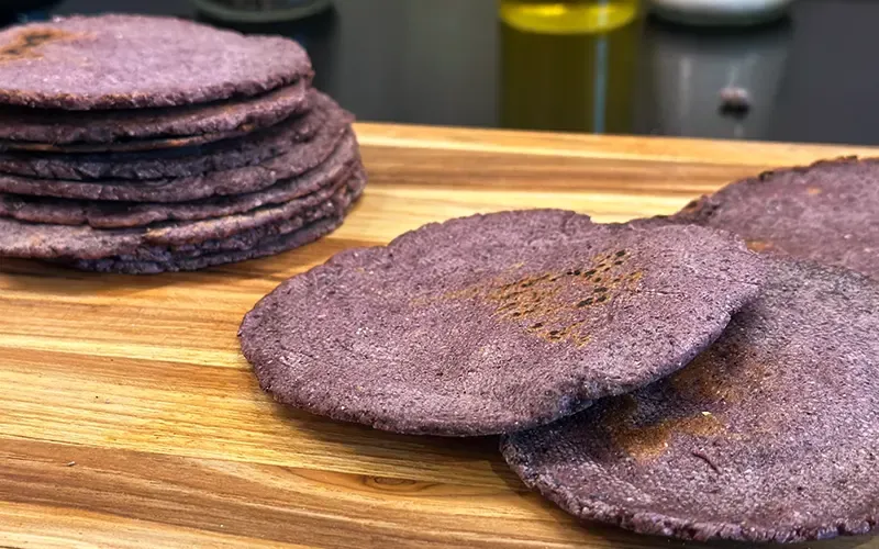Stack of homemade blue corn tortillas on a wooden board