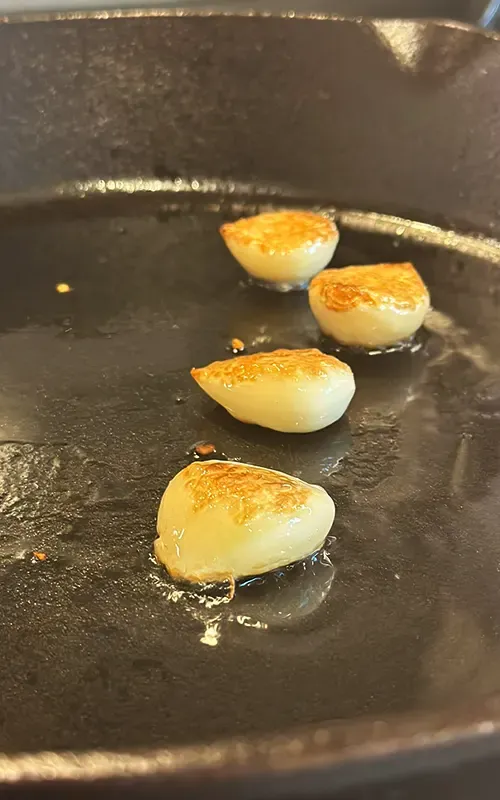 Garlic cloves toasting in a cast-iron skillet