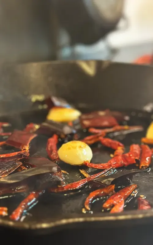 Dried chiles and garlic toasting in a cast-iron skillet