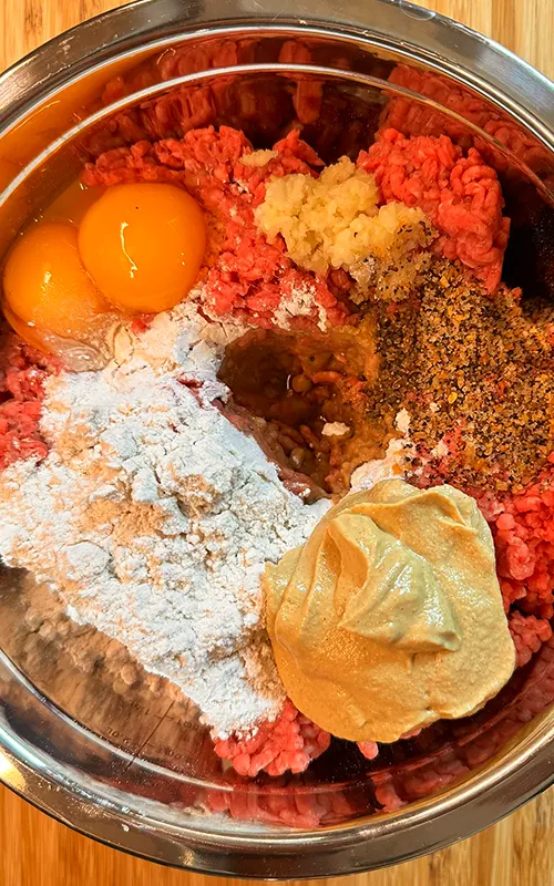 Ground Beef, Flour, Dijon Mustard, Garlic, Dijon Mustard, Montreal Steak Seasoning, and Egg Yolks in a mixing bowl for Burger Patties.